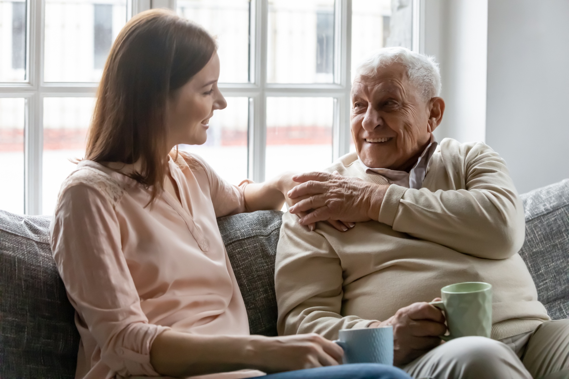 Aide-soignante échangeant avec un homme âgé souriant à domicile